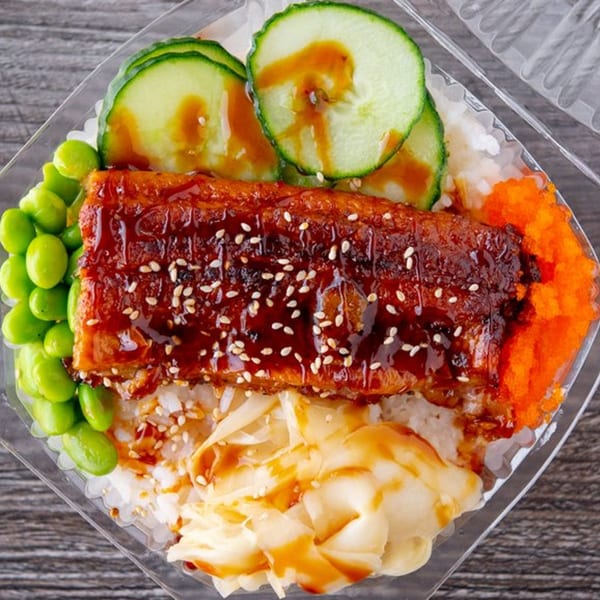 Poke bowl with glazed eel, edamame, cucumber, orange roe, and pickled ginger over rice.